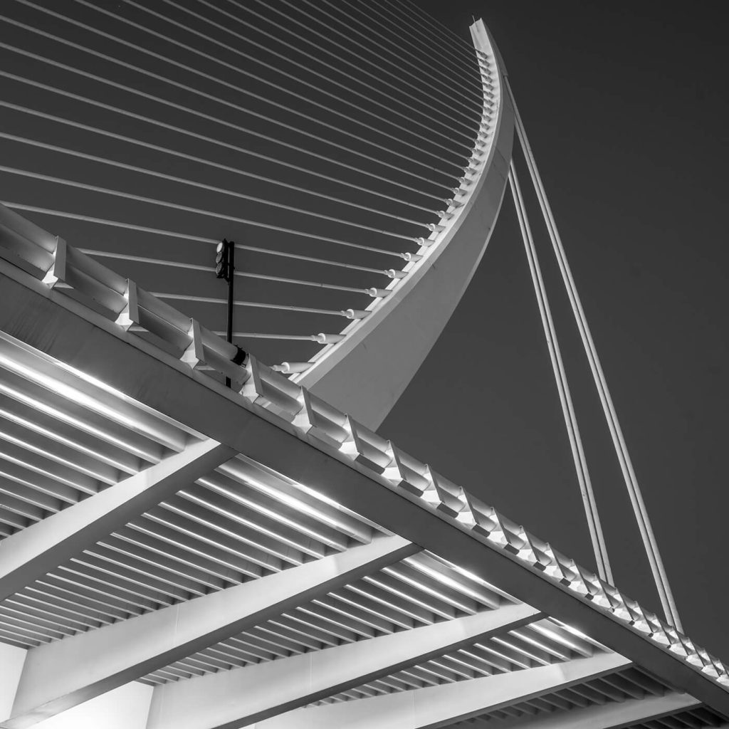 Photo en noir et blanc de la structure du Pont de l'Assut de l'Or à Valence, en Espagne, évoquant une arbalète.