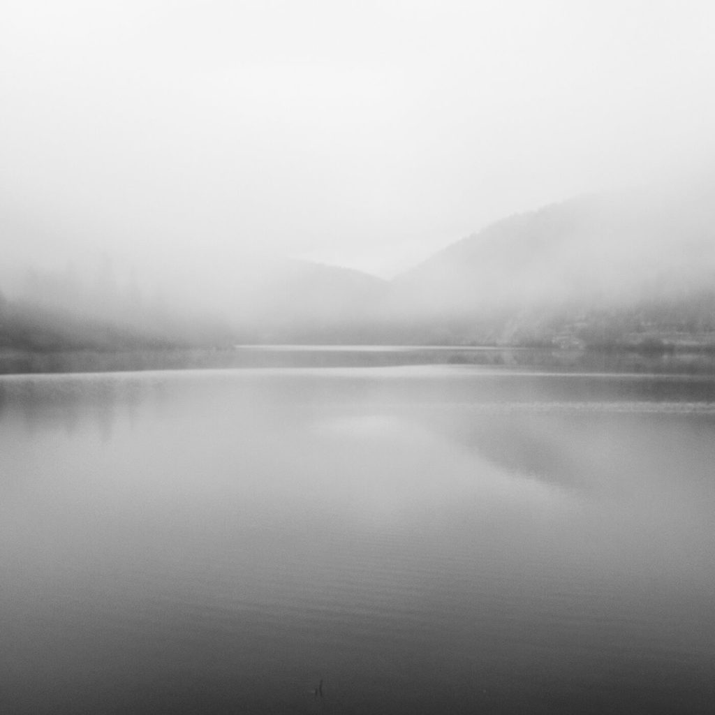 Photo en noir et blanc du lac de Sylans sous le brouillard dans l'Ain.