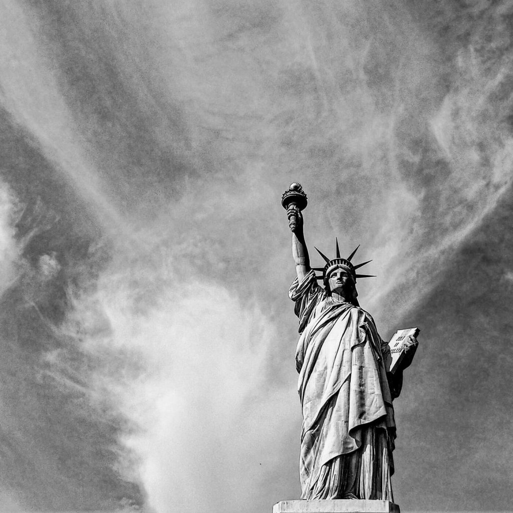 Photo en noir et blanc de la Statue de la Liberté avec le ciel de Manhattan à New York.