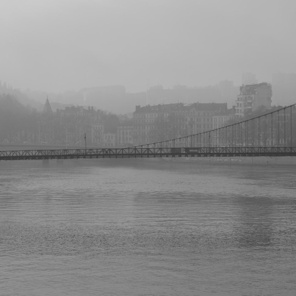 Photo en noir et blanc de la passerelle Masaryk à Lyon par une journée de brume.