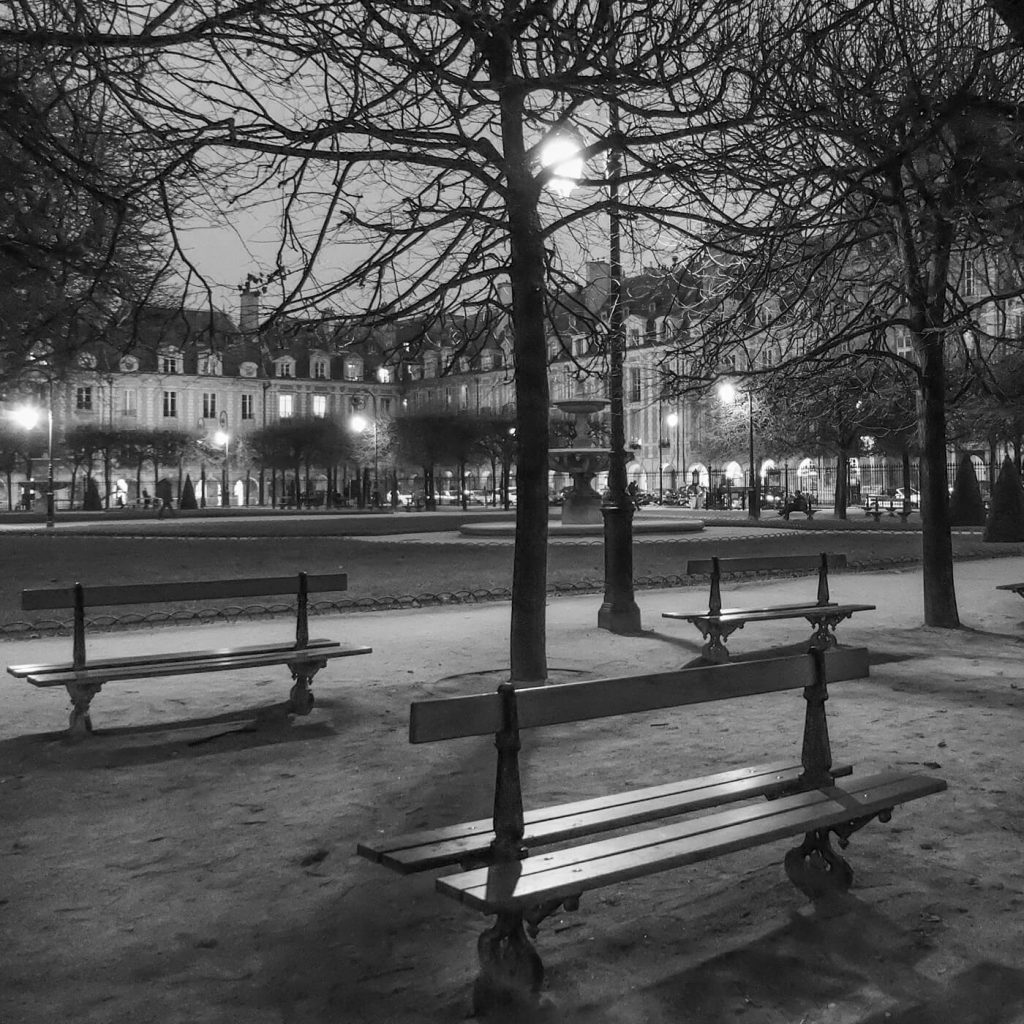 Photo en noir et blanc de la Place des Vosges de nuit, à Paris.