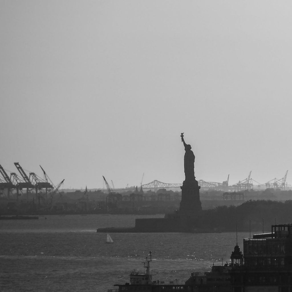 Photo en noir et blanc de la Statue de la Liberté avec des silhouettes mécaniques.